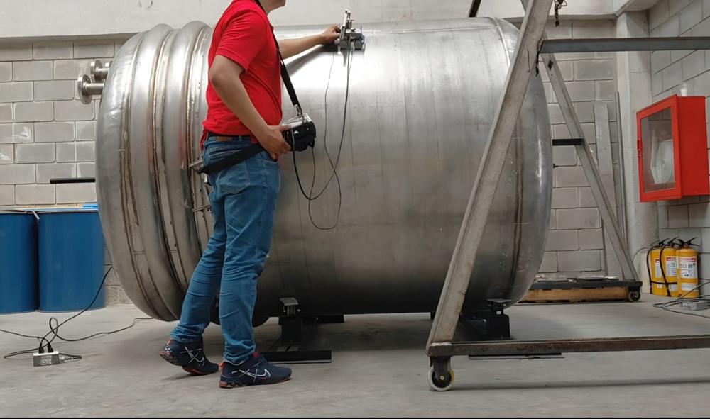 Inspector con equipo de partículas magnéticas en tanque industrial
